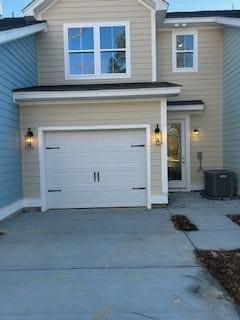 exterior space featuring central air condition unit, an attached garage, and driveway