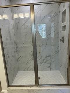 bathroom featuring a marble finish shower