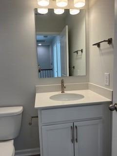 half bath with vanity, toilet, and baseboards