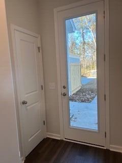 doorway featuring dark wood-style floors and baseboards