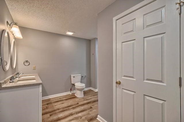 bathroom featuring hardwood / wood-style floors, vanity, toilet, and a textured ceiling