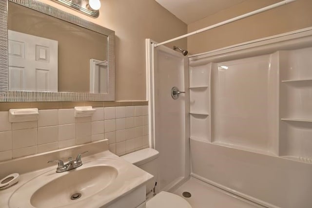 bathroom with vanity, toilet, a shower, and tasteful backsplash