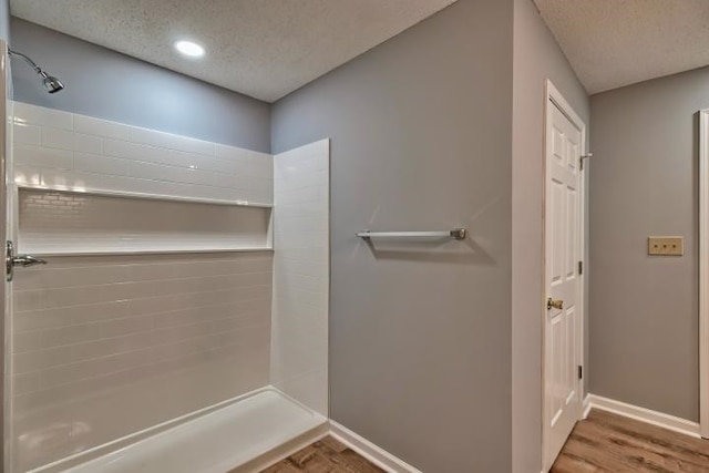 bathroom featuring hardwood / wood-style floors, a shower, and a textured ceiling