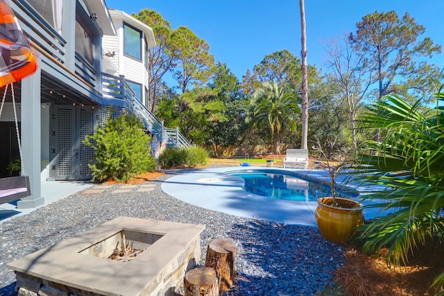 pool featuring stairway, a patio area, and a fire pit