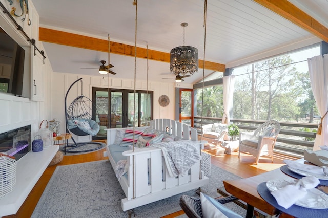 living area with a decorative wall, wood finished floors, french doors, beam ceiling, and a glass covered fireplace