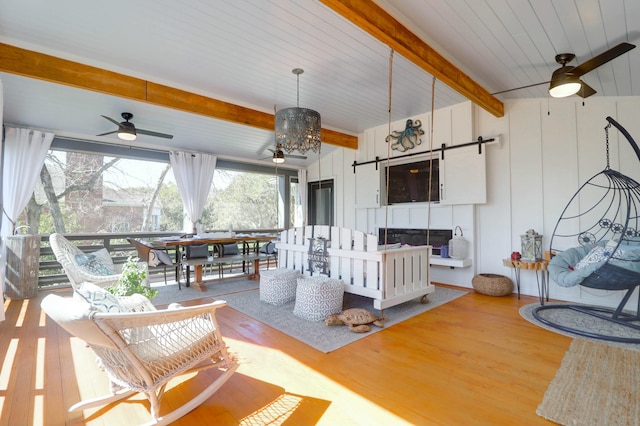 sunroom featuring ceiling fan, a fireplace, and beam ceiling