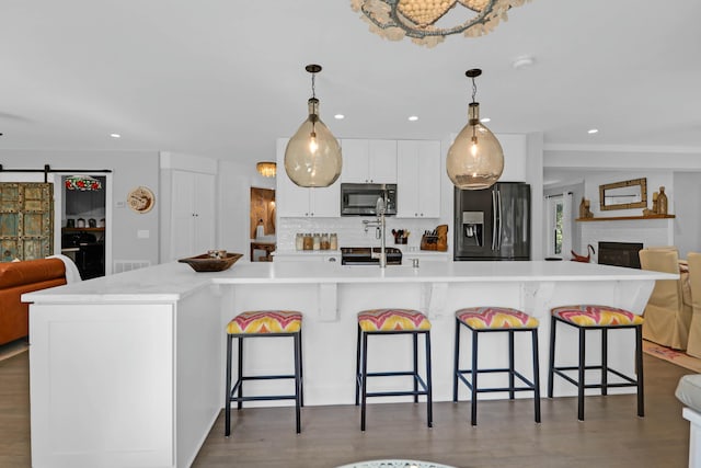 kitchen featuring pendant lighting, light countertops, a barn door, appliances with stainless steel finishes, and open floor plan