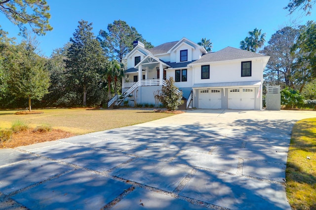 view of front of property featuring driveway, a chimney, an attached garage, stairs, and a front lawn