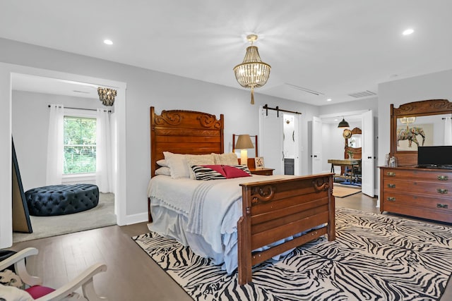 bedroom with dark wood finished floors, recessed lighting, visible vents, a barn door, and baseboards