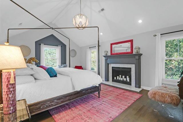 bedroom with multiple windows, vaulted ceiling, visible vents, and wood finished floors