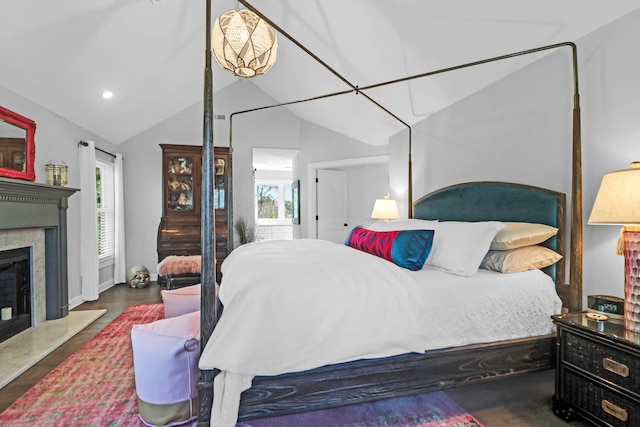 bedroom featuring dark wood-style floors, multiple windows, vaulted ceiling, and a high end fireplace