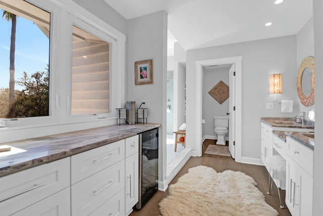 kitchen featuring dark wood finished floors, recessed lighting, stone countertops, white cabinets, and baseboards