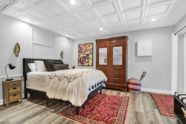 bedroom featuring light wood finished floors, an ornate ceiling, baseboards, and recessed lighting