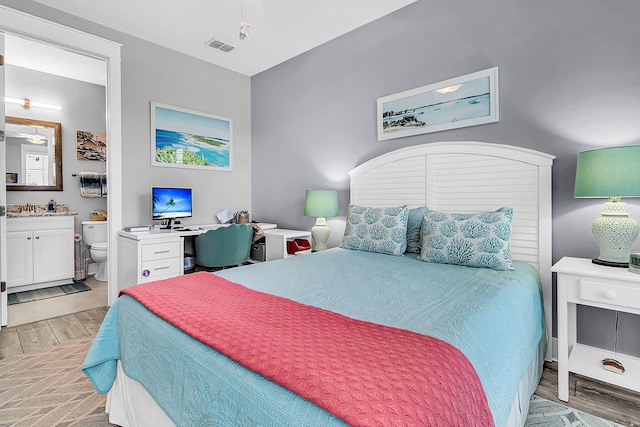 bedroom with sink, ensuite bath, and light hardwood / wood-style floors