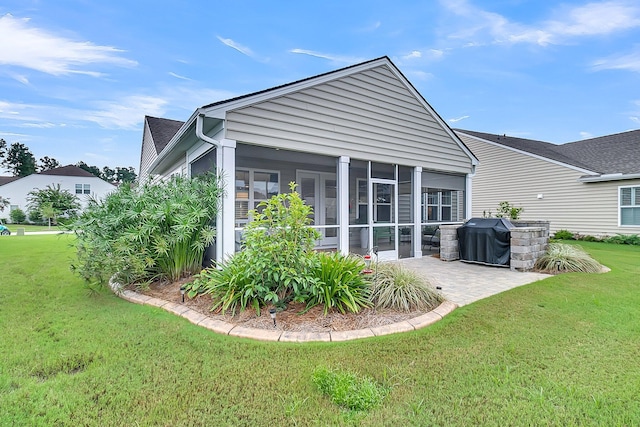 back of property with a yard, a patio, and a sunroom