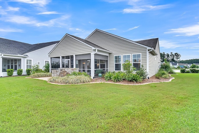 back of property with a sunroom and a lawn