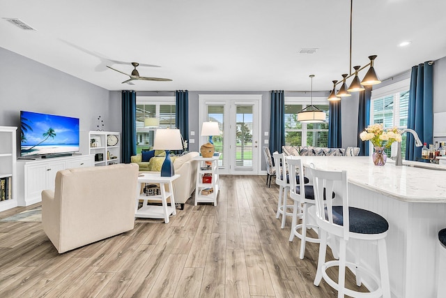 living room with sink, ceiling fan, and light wood-type flooring