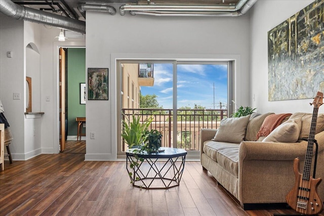 living room with a towering ceiling and dark hardwood / wood-style flooring