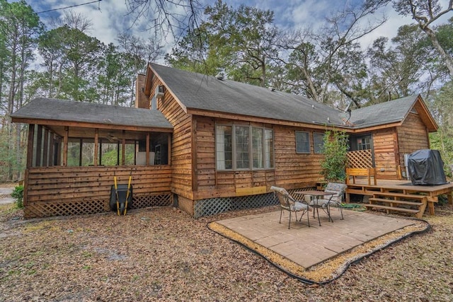 rear view of house featuring a deck, a patio, crawl space, and a sunroom