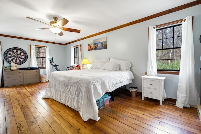 bedroom featuring crown molding, visible vents, a ceiling fan, and hardwood / wood-style floors