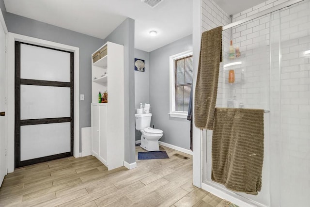 bathroom featuring baseboards, visible vents, toilet, wood finished floors, and a shower stall