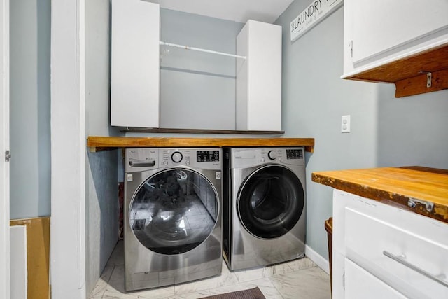 laundry area featuring marble finish floor, baseboards, cabinet space, and washing machine and clothes dryer