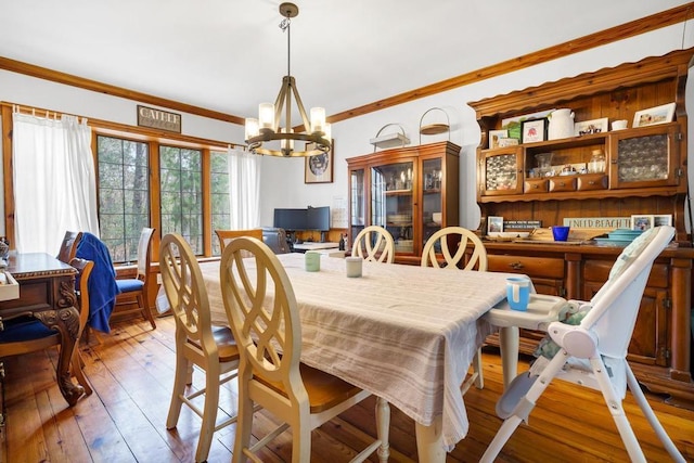 dining area with an inviting chandelier, crown molding, and hardwood / wood-style floors