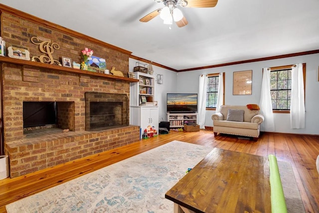 living room with ornamental molding, a brick fireplace, ceiling fan, and hardwood / wood-style floors