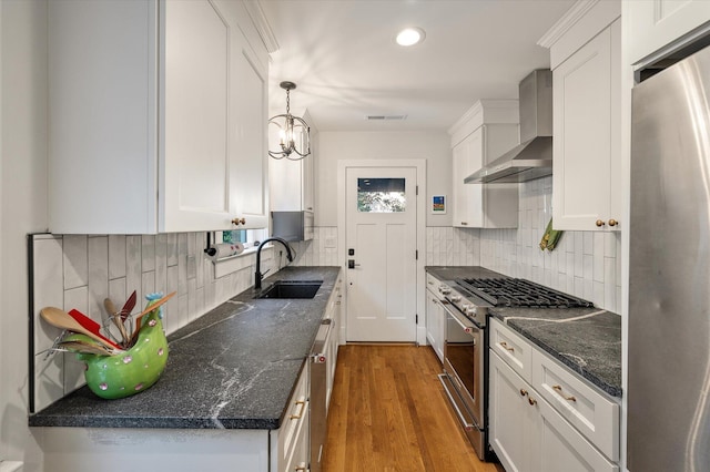 kitchen featuring visible vents, a sink, white cabinetry, appliances with stainless steel finishes, and wall chimney range hood