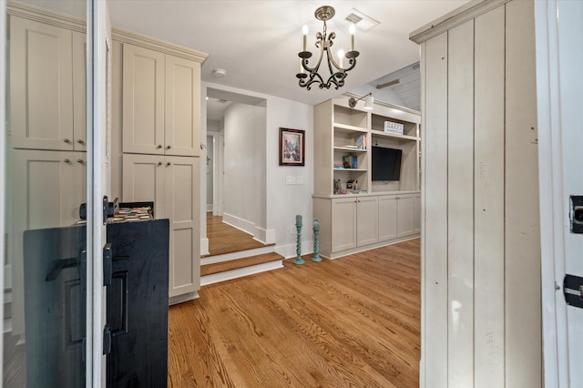 hall featuring visible vents, baseboards, an inviting chandelier, and light wood-style flooring