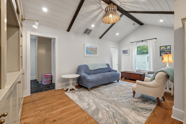 living area featuring lofted ceiling with beams, visible vents, and wood finished floors