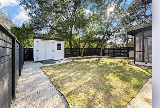 view of yard with a shed, an outdoor structure, a fenced backyard, and a sunroom