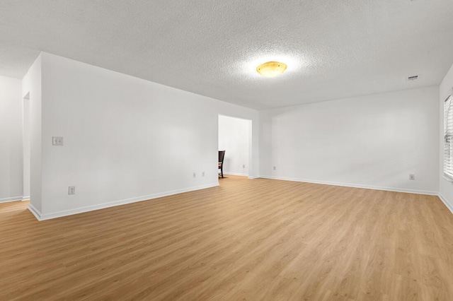 empty room with a textured ceiling and light wood-type flooring