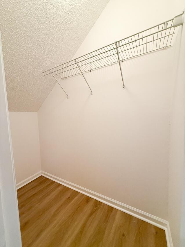 walk in closet with hardwood / wood-style floors and vaulted ceiling