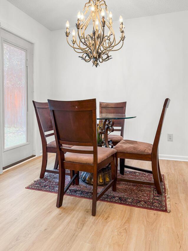 dining room with a notable chandelier, wood-type flooring, and a textured ceiling