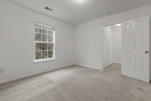 spare room with light colored carpet and a textured ceiling