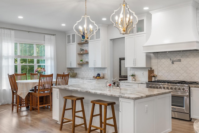 1130 Plantation Overlook Dr, Moncks Corner, SC 29461 - kitchen with stainless steel stove, custom exhaust hood, an island with sink, white cabinets, and backsplash