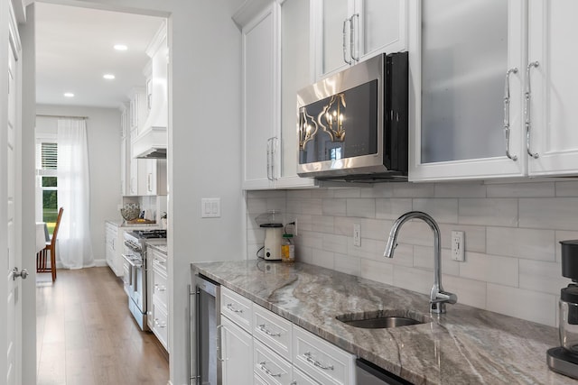 1130 Plantation Overlook Dr, Moncks Corner, SC 29461 - kitchen featuring stainless steel appliances, wine cooler, tasteful backsplash, white cabinets, and light wood-type flooring