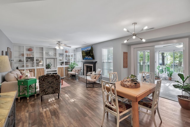 dining area with ceiling fan, visible vents, a fireplace, and wood finished floors