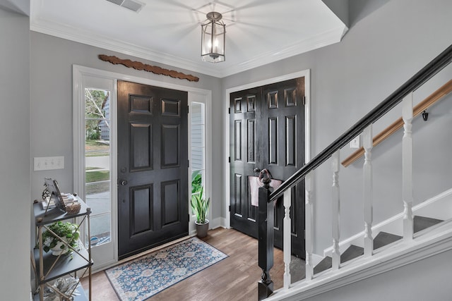 entrance foyer featuring visible vents, stairs, ornamental molding, and wood finished floors