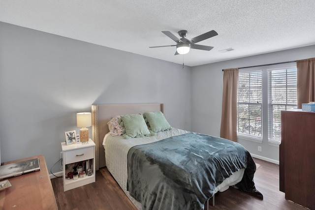 bedroom featuring baseboards, a textured ceiling, visible vents, and wood finished floors