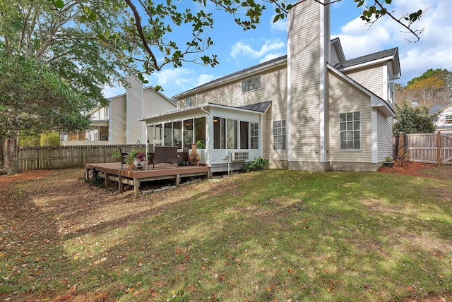 rear view of property featuring a chimney, a lawn, a sunroom, a fenced backyard, and a wooden deck