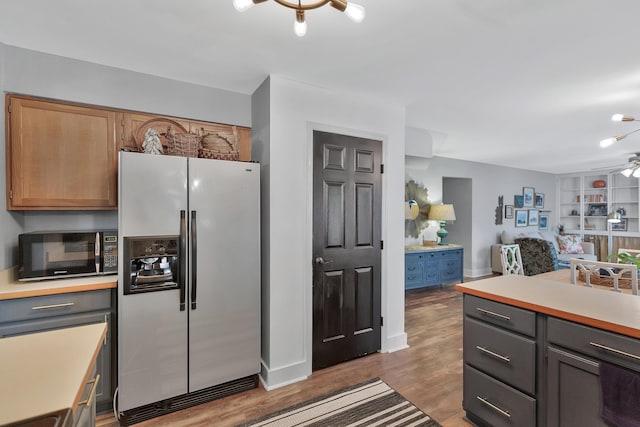 kitchen with light countertops, a ceiling fan, wood finished floors, black microwave, and stainless steel fridge