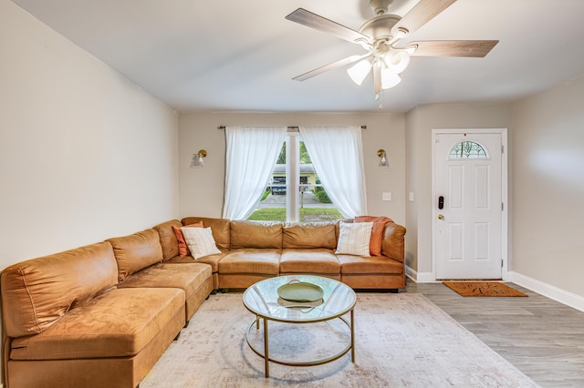 living room with baseboards, wood finished floors, and a ceiling fan