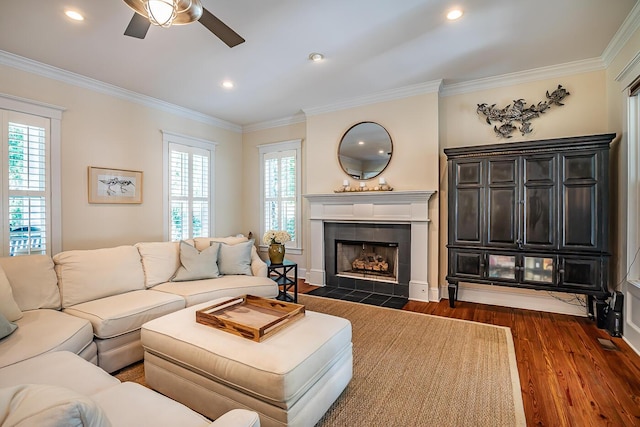 living room featuring a tiled fireplace, ceiling fan, a wealth of natural light, and dark hardwood / wood-style floors