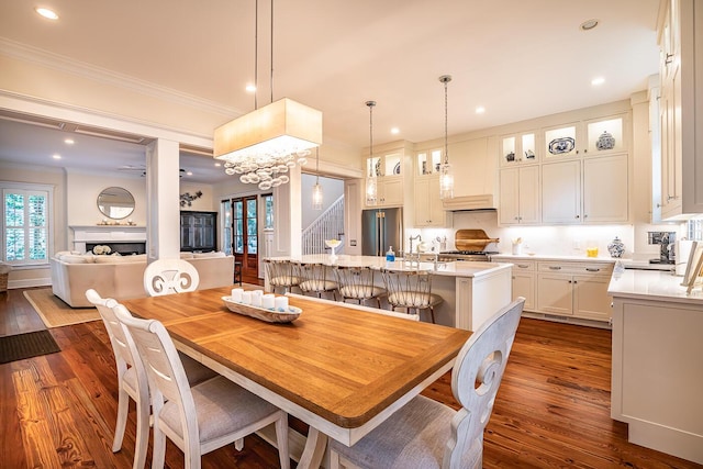 dining space with dark wood-type flooring, ornamental molding, and sink