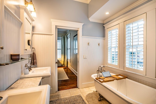 bathroom with tile patterned flooring, ornamental molding, a bathtub, and plenty of natural light