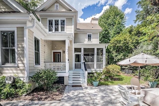 rear view of property featuring a sunroom and a patio area