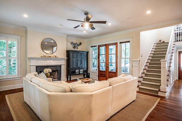 living room featuring a tiled fireplace, ceiling fan, crown molding, and dark hardwood / wood-style floors