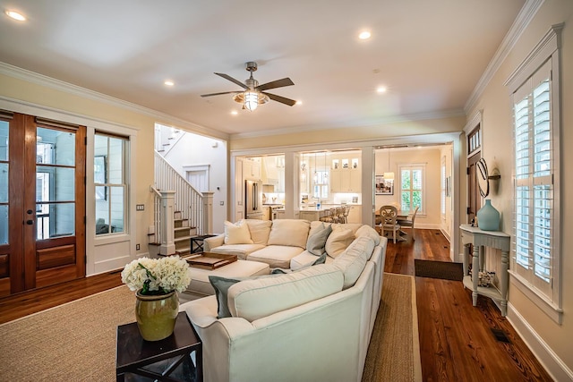 living room with ornamental molding, dark wood-type flooring, and ceiling fan